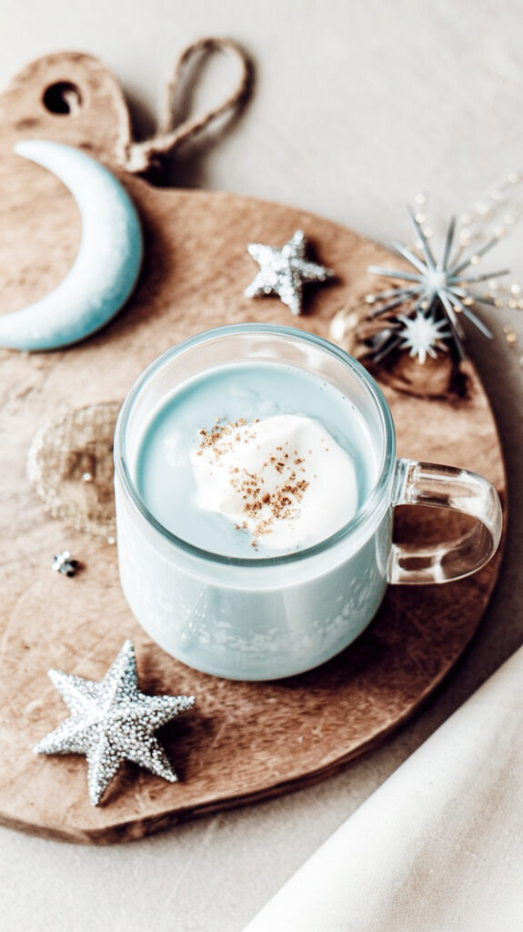 Adaptogenic blue moon milk for better sleep in a cozy glass mug, topped with frothy foam and dusted with cinnamon.