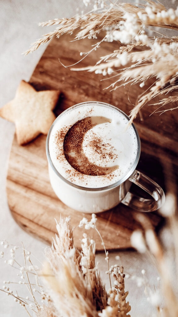 Adaptogenic moon milk for better sleep in a cozy glass mug, topped with frothy foam and dusted with cinnamon.